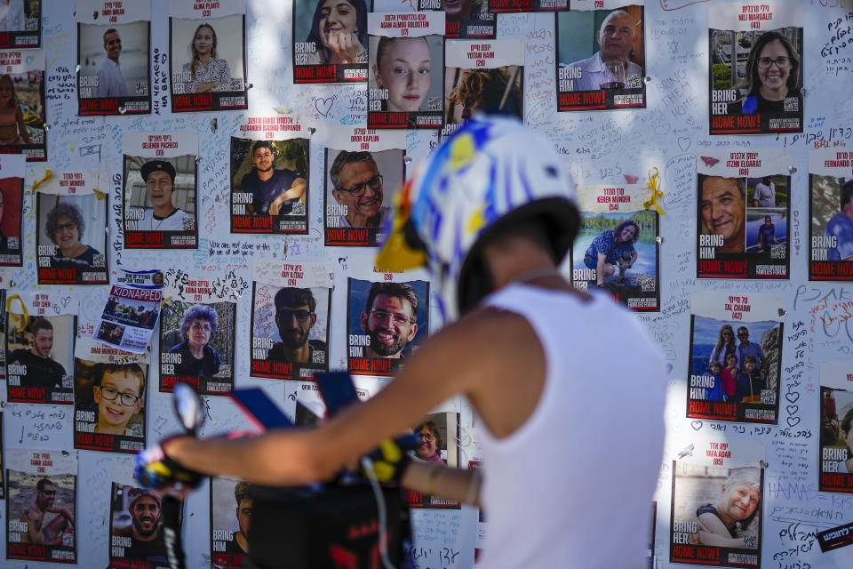 A man looks at photos of people kidnapped during the Oct. 7 Hamas bloody cross-border attack in Tel Aviv, Israel, Tuesday, Nov. 7, 2023. The Islamic militant group killed 1,400 people and kidnapped 240 others in an unprecedented cross-border attack on Oct. 7, triggering a war that has raged for the past month. (AP Photo/Ariel Schalit)