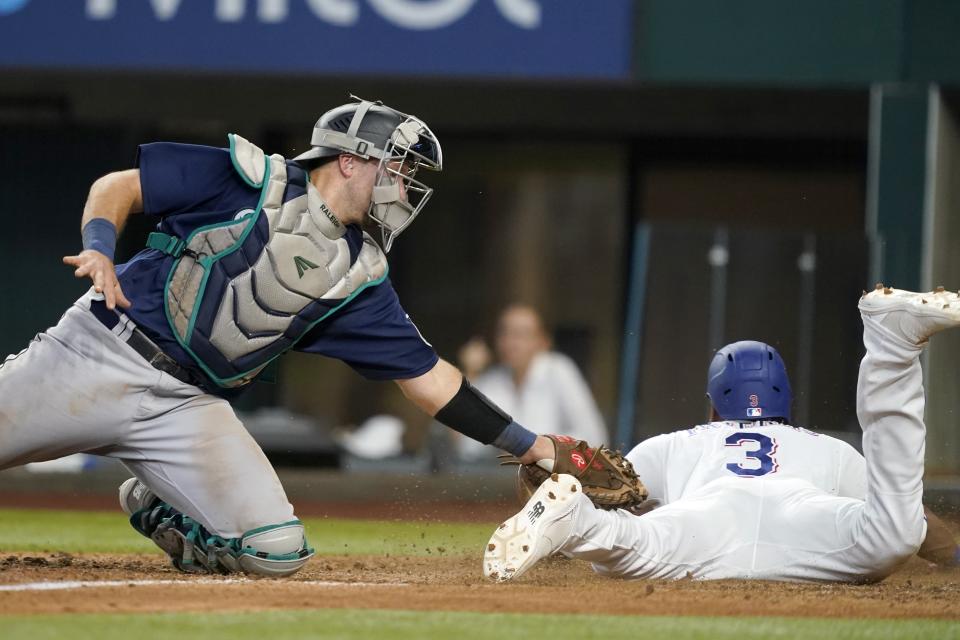 Seattle Mariners catcher Cal Raleigh attempts to tag Texas Rangers' Leody Taveras who scored on a Elier Hernandez single in the seventh inning of a baseball game, Saturday, July 16, 2022, in Arlington, Texas. (AP Photo/Tony Gutierrez)