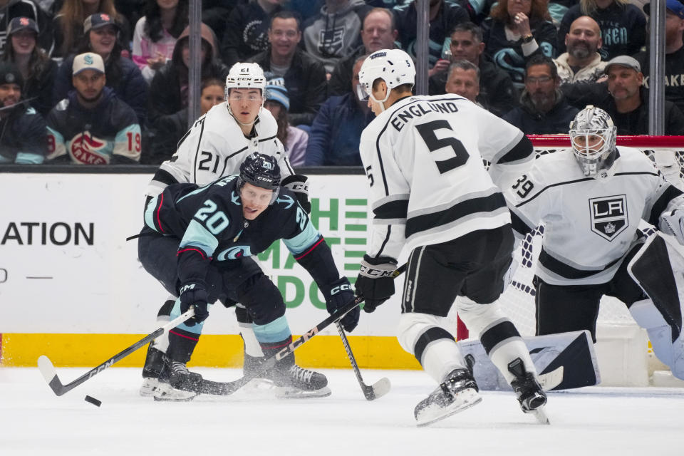 Seattle Kraken right wing Eeli Tolvanen (20) reaches out for the puck as Los Angeles Kings defenseman Jordan Spence (21) and defenseman Andreas Englund (5) look on with goaltender Cam Talbot (39) during the second period of an NHL hockey game Saturday, Dec. 16, 2023, in Seattle. (AP Photo/Lindsey Wasson)