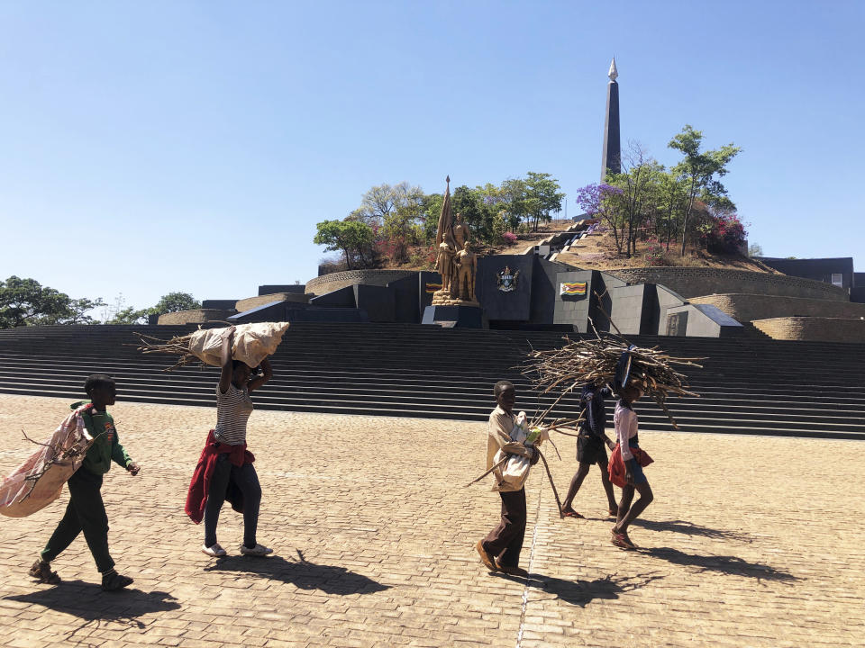 Children carry firewood near the place where former Zimbabwean President Robert Mugabe was supposed to be buried at the National Heroes Acre, in Harare, Friday, Sept, 27, 2019. Zimbabwe's former president Mugabe will now be buried at his rural home, according to a government spokesperson. Mugabe's burial location has been a source of mystery and contention since his death earlier this month at age 95 in Singapore. (AP Photo/Tsvangirayi Mukwazhi)