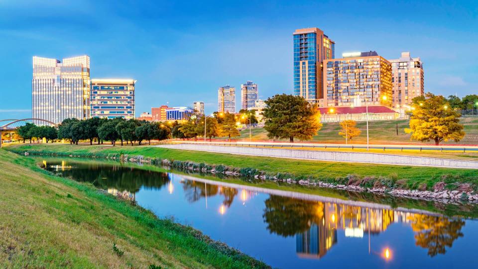 Panoramic photo of the skyline of Fort Worth with apartments and office buildings reflecting in the Clear Fork Trinity River at Trinity Park, in downtown Fort Worth,Texas, USA.