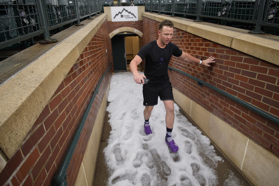 Colorado Rockies assistant bullpen catcher Kyle Cunningham navigates a hail-covered walkway to the field after a storm Thursday, June 29, 2023, in Denver. The Rockies were scheduled to play against the Los Angeles Dodgers. (AP Photo/David Zalubowski)
