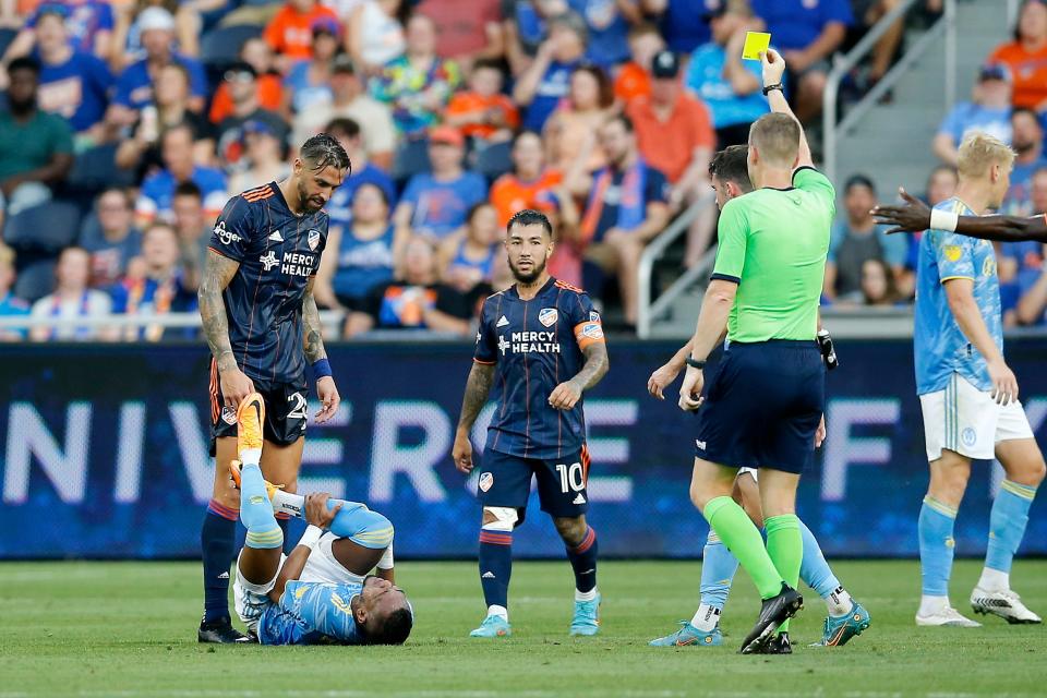 FC Cincinnati defender Geoff Cameron (20) stands over  Philadelphia Union midfielder José Andrés Martínez (8) as he receives a yellow card in the first half of the MLS match between FC Cincinnati and Philadelphia Union at TQL Stadium in Cincinnati on Saturday, Aug. 6, 2022. The game was tied 0-0 at halftime. 