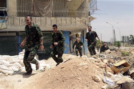 Forces loyal to Syria's President Bashar al-Assad run through Aleppo's Bustan al-Qasr crossing after their release by rebels May 7, 2014. REUTERS/George Ourfalian