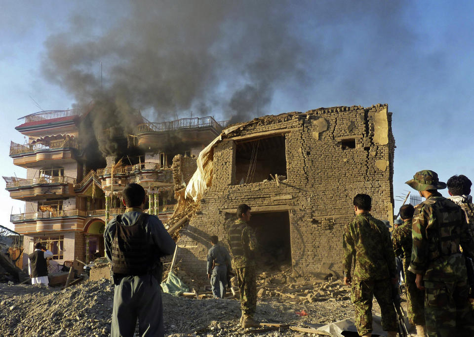 FILE - In this file photo, Afghan security force members stand outside a USAID compound in Kunduz, northern Afghanistan, Friday, July 2, 2010 after it was stormed by militants wearing suicide vests. After 20 years America is ending its “forever” war in Afghanistan. There’s conflicting views even among U. S. military minds as to whether the time is right. For others there is another lingering question: Was it worth it? (AP Photo)