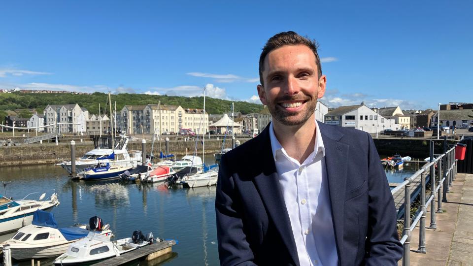 Man wearing open-collared shirt and suit outside marina