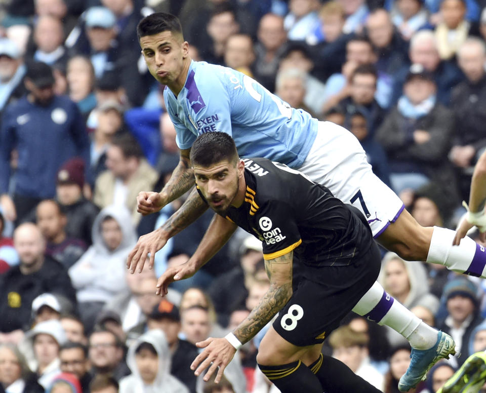 Wolverhampton Wanderers' Ruben Neves and Manchester City's Joao Cancelo, top, clash during the English Premier League soccer match between Manchester City and Wolverhampton Wanderers at Etihad stadium in Manchester, England, Sunday, Oct. 6, 2019. (AP Photo/Rui Vieira)