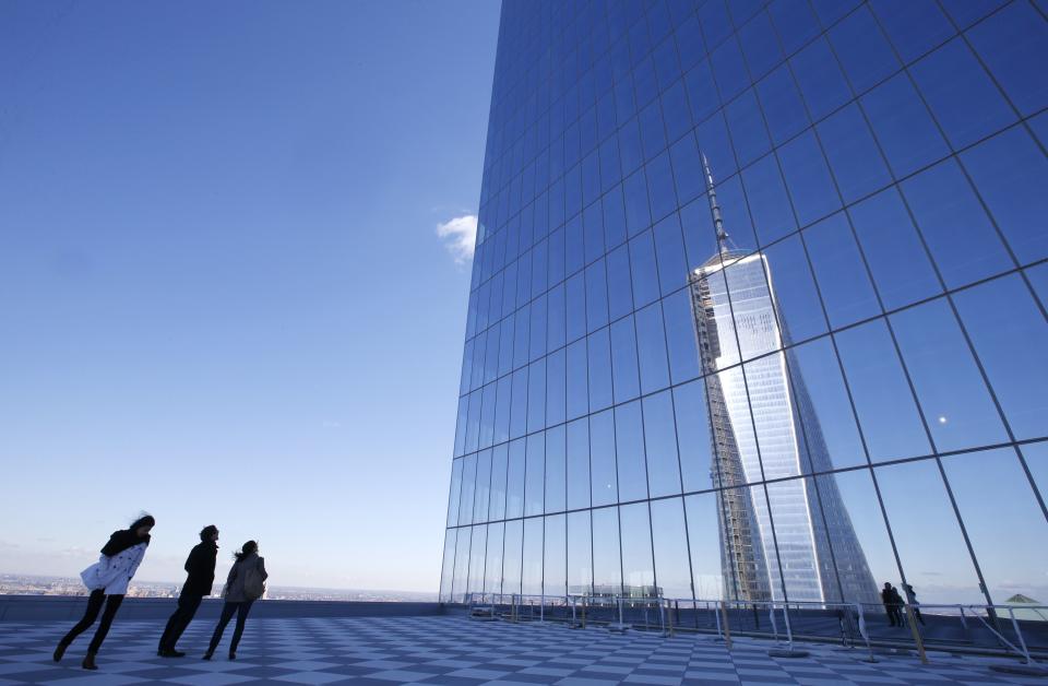 People look up at a reflection of the One World Trade Center tower from a terrace on the 57th floor of the soon to be opened 4 World Trade Center tower in New York