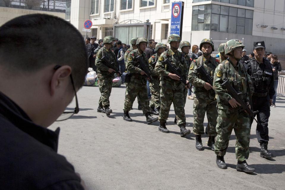 Heavily armed Chinese paramilitary policemen march past the site of the Wednesday's explosion outside the Urumqi South Railway Station in Urumqi in northwest China's Xinjiang Uygur Autonomous Region Thursday, May 1, 2014. Chinese President Xi Jinping has demanded 'decisive actions" against terrorism following the attack at the railway station in the far west minority region of Xinjiang that left three people dead and 79 injured. (AP Photo/Ng Han Guan)