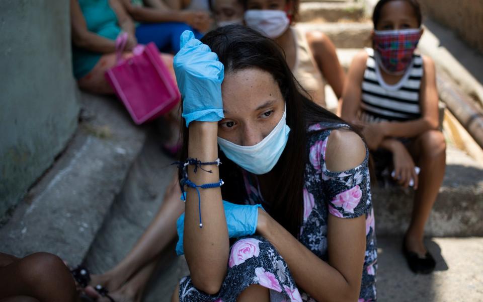 A woman waits outside a soup kitchen in Caracas' Petare slum in Venezuela - AP