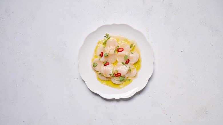 scallop crudo with yuzu and chile on white plate