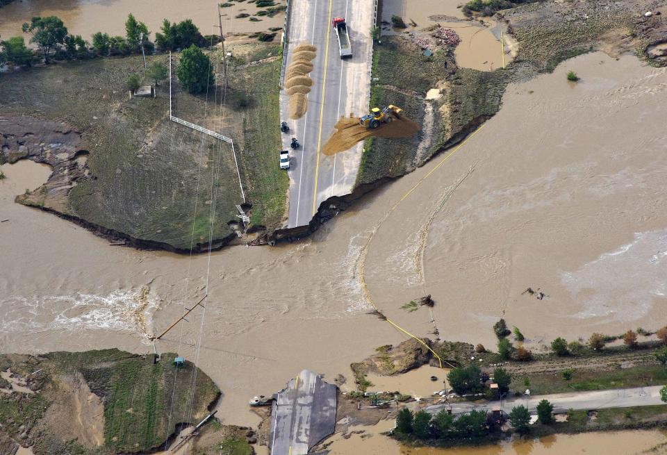 A road crew works on a stretch of highway washed out by flooding along the South Platte River in Weld County, Colorado near Greeley, Saturday, Sept. 14, 2013.  Hundreds of roads in the area have been damaged or destroyed by the floodwaters that have affected parts of a 4,500-square-mile (11,655-square-kilometer) area — an area the size of the U.S. state of Connecticut. (John Wark/AP)