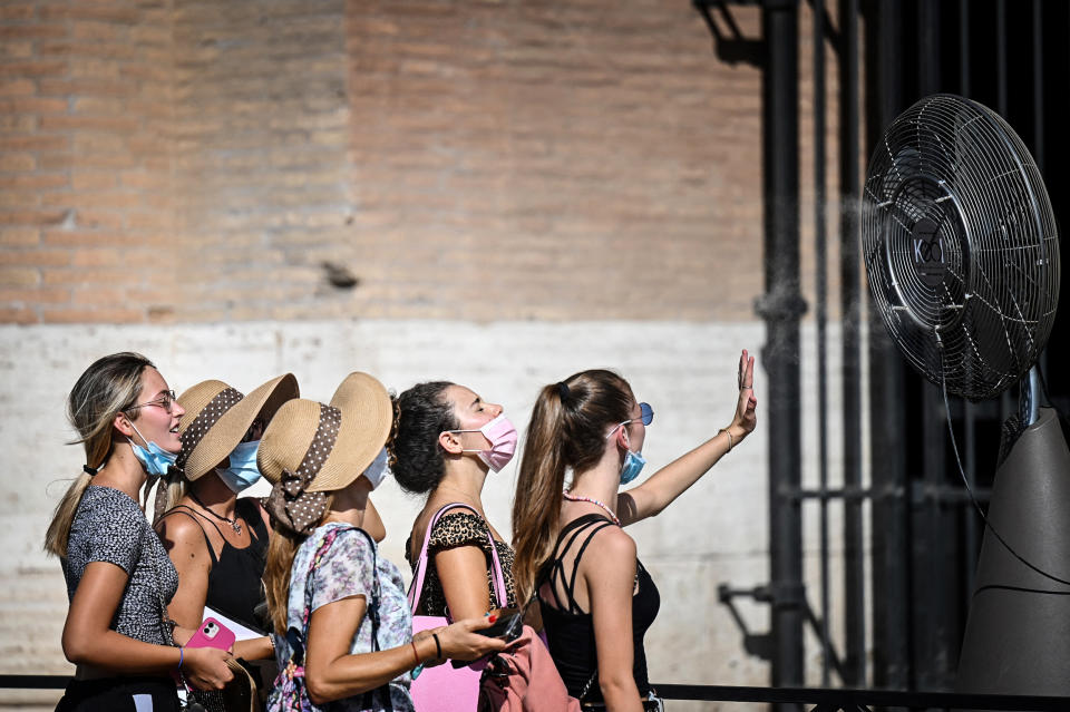 A group of woman cool off in front of a cooling fan during a heatwave as they queue at the entrance of the Colosseum in Rome on Aug. 12, 2021. (Alberto Pizzoli / AFP via Getty Images file)