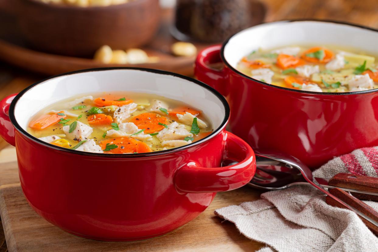 Closeup of two bowls of chicken noodle and vegetable soup soup on a wooden table