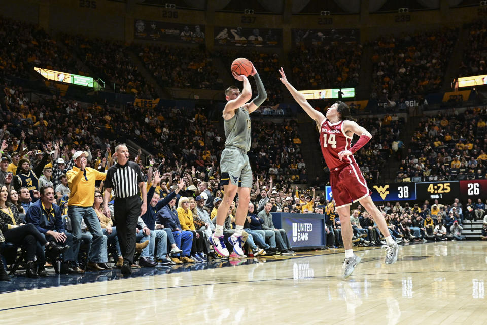 West Virginia guard Erik Stevenson (10) shoots a 3-point basket while guarded by Oklahoma guard Bijan Cortes (14) during the first half of an NCAA college basketball game in Morgantown, W.Va., Saturday, Feb. 4, 2023. (AP Photo/William Wotring)