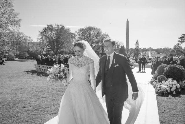 A black and white photo shows Naomi Biden and Peter Neal walking down the aisle after their wedding reception on the South Lawn of the White House.