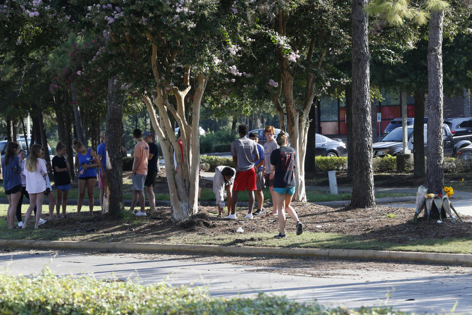 Students and friends of Salma Gomez and Chloe Robison gather at a small memorial near the site of a fatal car crash that killed the two teens, Wednesday, July 25, 2018, in Atascocita, Texas. Authorities in Texas say a teen driver will face criminal charges after a violent crash that split his vehicle in half and killed two 16-year-old passengers. (Steve Gonzales/Houston Chronicle via AP)