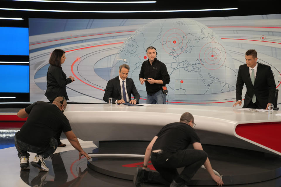 Technicians prepare a studio before the interview of Greece's Prime Minister and New Democracy leader Kyriakos Mitsotakis, center, with the journalist Antonis Sroiter, right, at Alpha television station during his election campaign in northern Athens, Greece, Tuesday, April 25, 2023. (AP Photo/Thanassis Stavrakis)