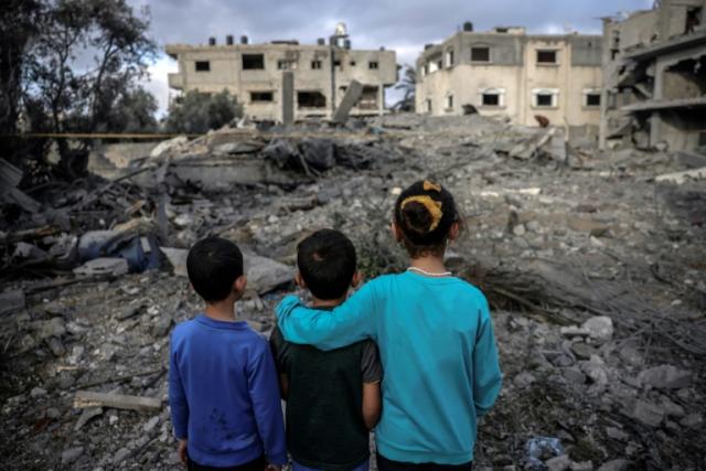 Children stand amidst the rubble of a building hit by an Israeli air strike in Deir al-Balah in the centre of the Gaza Strip