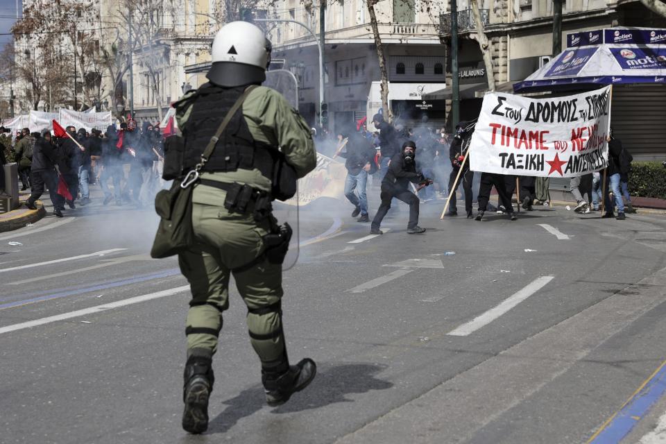 A hooded demonstrator clashes against riot police outside the Greek parliament in Athens, Greece, Sunday, March 5, 2023. Thousands protesters, take part in rallies around the country for fifth day, protesting the conditions that led the deaths of dozens of people late Tuesday, in Greece's worst recorded rail accident. (AP Photo/Yorgos Karahalis)