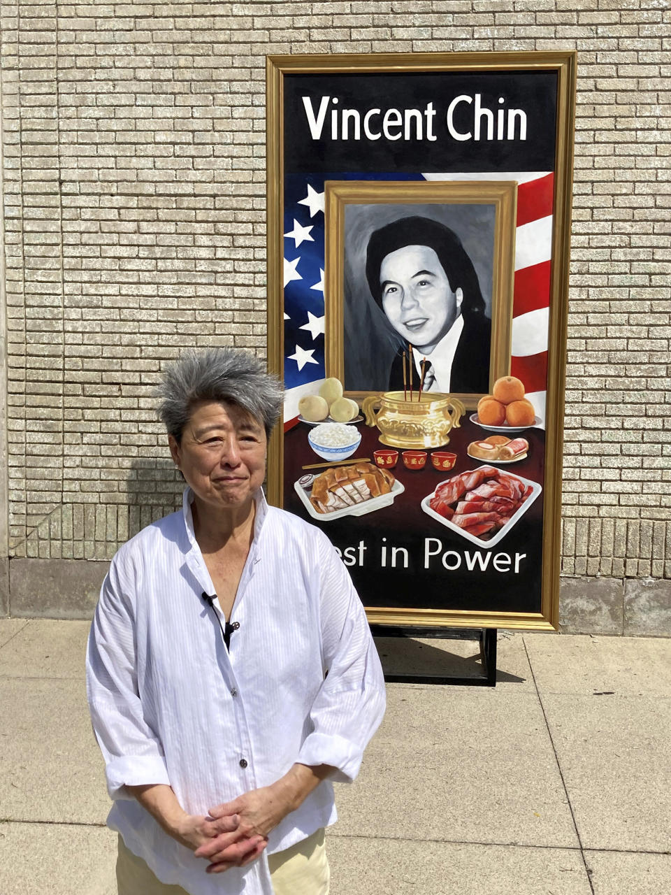 Activist and author Helen Zia poses Thursday, June 15, 2022, next to a painting of Vincent Chin in Detroit. The city is partnering with The Vincent Chin 40th Remembrance & Rededication Coalition to honor civil rights efforts that began with Chin's 1982 slaying. Chin, a Chinese American, was beaten to death in Detroit by two white men who never served jail time. The commemoration comes as hate crimes against Asian Americans are on the rise in the U.S. (AP Photo/Corey Williams)