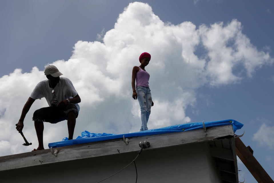 Devon Warner and his daughter Che Niesha work on the roof of a home at Codrington on the island of Barbuda just after a month after Hurricane Irma struck the Caribbean islands of Antigua and Barbuda