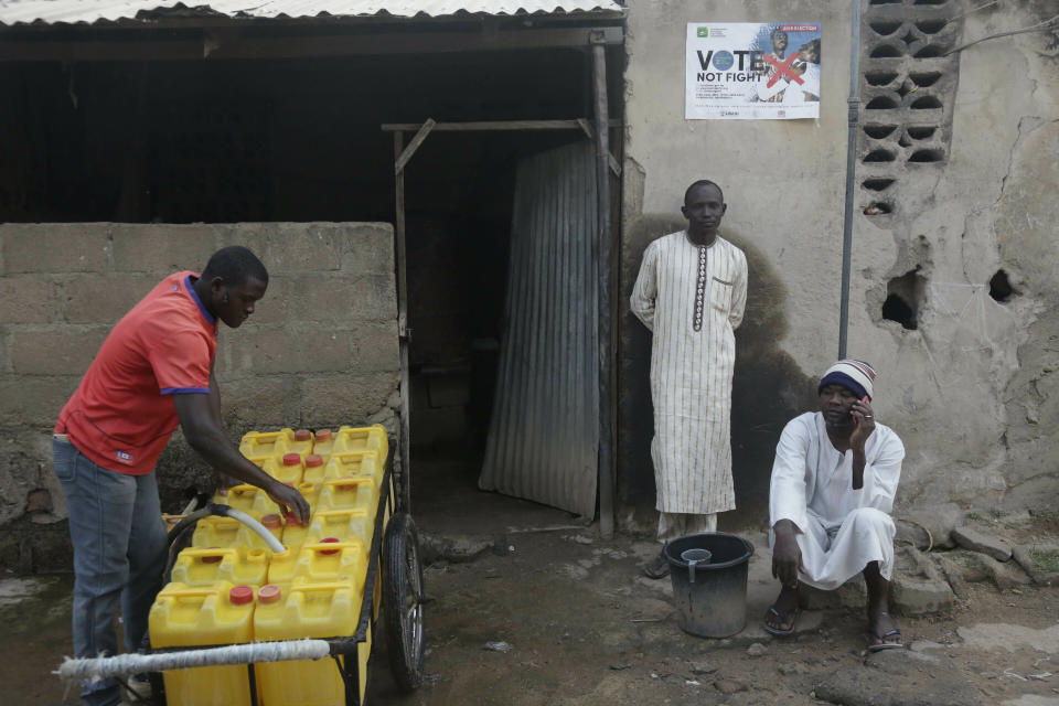 Men seen outside a house, near a polling station following the presidential election being delayed by the Independent National Electoral Commission in Yola, Nigeria, Saturday, Feb. 16, 2019. A civic group monitoring Nigeria's now-delayed election says the last-minute decision to postpone the vote a week until Feb. 23 "has created needless tension and confusion in the country." (AP Photo/Sunday Alamba)