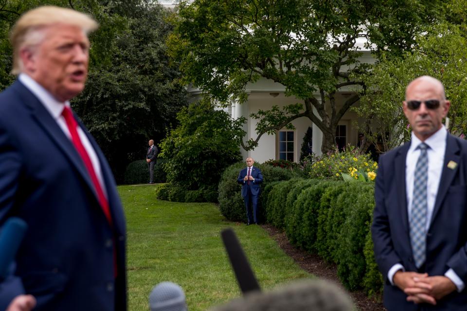 Members of the Secret Service, including Tony Ornato, right, stand guard as then-President Donald Trump, left, speaks to reporters on the South Lawn of the White House in 2019.