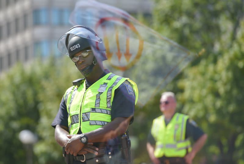 FILE PHOTO: Flag, bearing a leftist symbol associated with Antifa, is reflected behind a Boston Police officer during the Straight Pride Parade rally in Boston