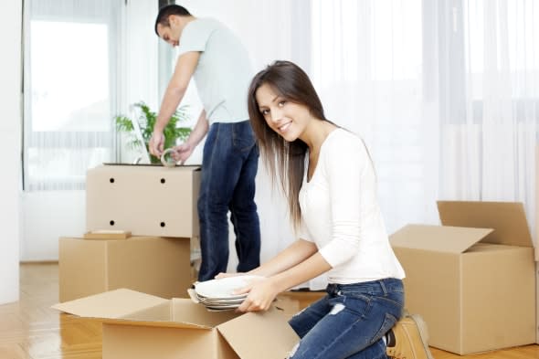 Portrait of an happy couple unpacking boxes, moving to new house