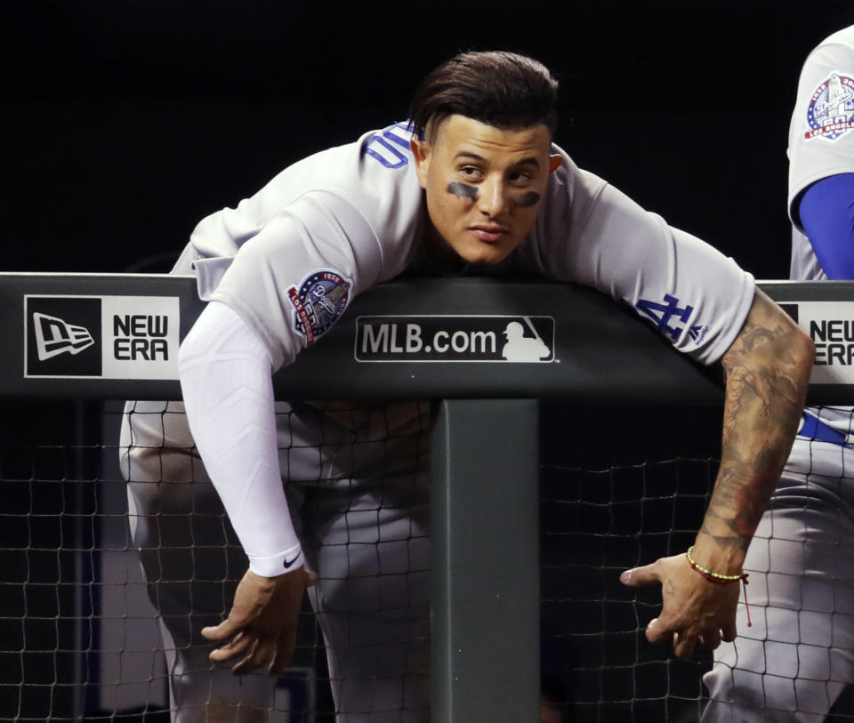 Los Angeles Dodgers shortstop Manny Machado hangs over the dugout rail to watch the Dodgers bat against the Colorado Rockies during the ninth inning of a baseball game Saturday, Aug. 11, 2018, in Denver. The Rockies won 3-2. (AP Photo/David Zalubowski)