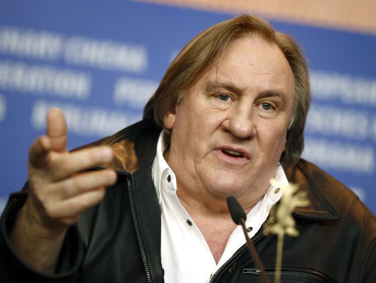 Actor Gerard Depardieu gestures with his hand behind a microphone