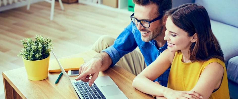 Happy couple with laptop spending time together at home