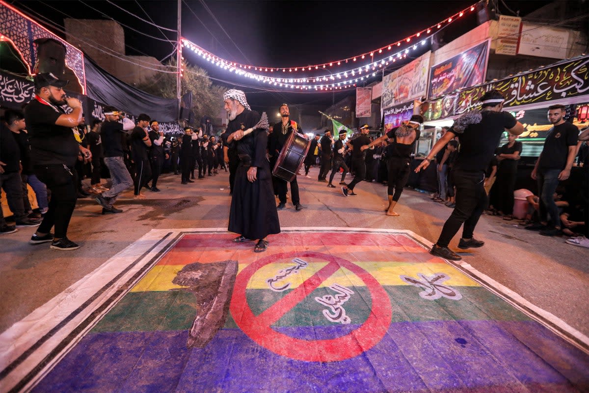 Shia Muslim devotees self-flagellate over an unfurled banner on the ground depicting the Pride rainbow flag defaced with a boot and the Arabic slogan ‘no to homosexual society’ in the city of Nasiriyah in Iraq (AFP/Getty)