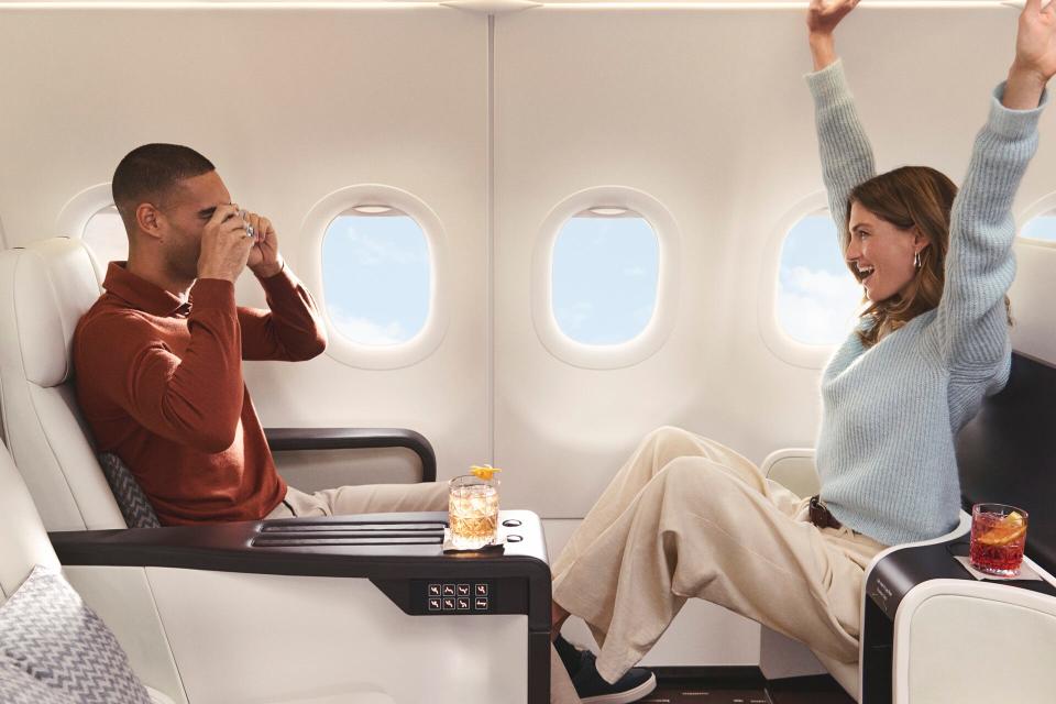 A man takes a picture of a woman cheering on board an Airbus A321LR Four Seasons