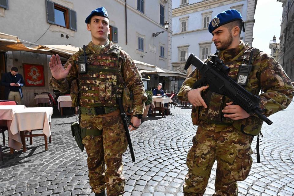 Soldiers patrol past an empty restaurant in the Trastevere district of Rome (AFP via Getty Images)
