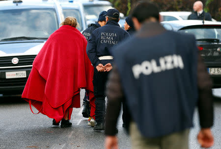 A person is escorted by local police after they confiscated a villa built illegally by an alleged Mafia family in Rome, Italy, November 20, 2018. REUTERS/Yara Nardi