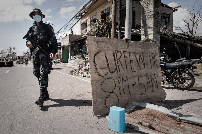 A soldier keeps vigil at a checkpoint where a curfew sign is displayed, on the 7th day of the Typhoon Haiyan disaster, in Tacloban, on the eastern island of Leyte, on November 15, 2013