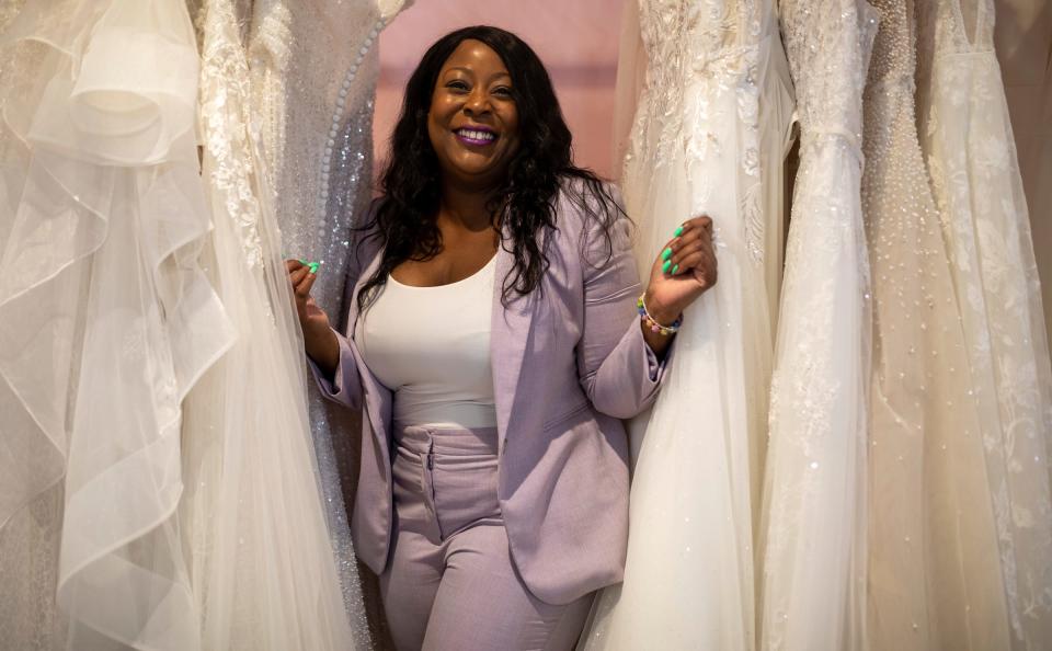 Raeshawn Bumphers, owner of Pink Poodle Dress Lounge, stands alongside a couple of her dresses in Detroit on Thursday, June 1, 2023. According to Bumphers, she removed blight from three locations since opening her store in 2018.