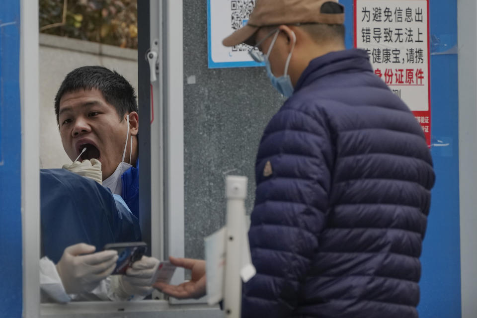 A man has his throat swabbed for a COVID-19 test at a coronavirus testing site in Beijing, Tuesday, Nov. 22, 2022. Anti-virus controls that are confining millions of Chinese families to their homes and shut shops and offices are spurring fears already weak global business and trade might suffer. (AP Photo/Andy Wong)