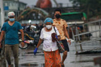 People wear face masks as they walk outside the Dala jetty in Yangon, Myanmar Tuesday, July 27, 2021. (AP Photo)