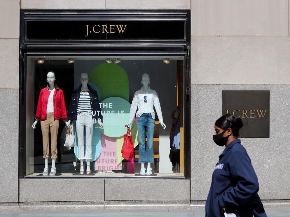 Woman wearing mask walks past J. Crew store that's window says "the future is bright"