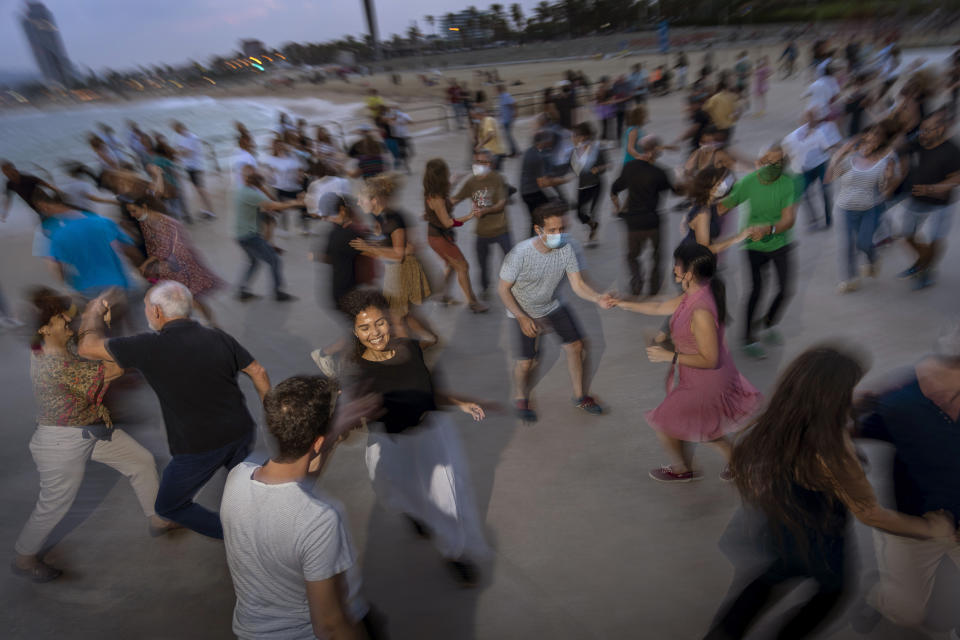 People dance on a promenade facing the mediterranean sea as the sun sets at a beach in Barcelona, Spain, Sunday, Oct. 3, 2021. Every Sunday swing lovers gather to dance in front of the sea organized by the swing dance school MesqueSwing_Poblenou. (AP Photo/Emilio Morenatti)