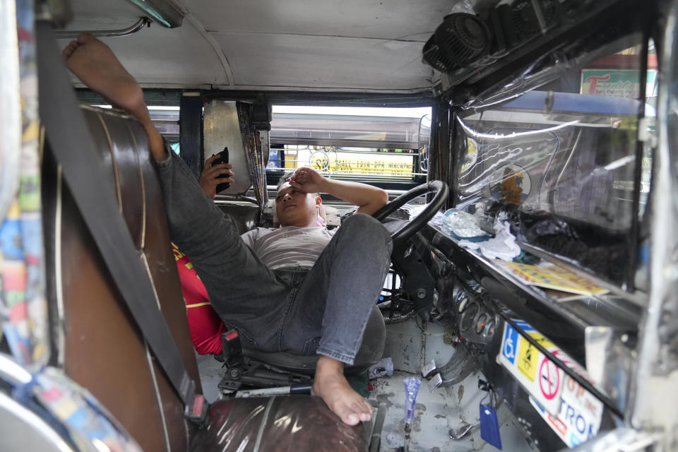 Jeepney driver Raymond Manaog, 29, watches on his smart phone as he waits in line at passenger terminal in Pasay, Philippines Tuesday, Oct. 11, 2022. Manaog complains that inflation, and especially the rising price of diesel, is forcing him to work more to get by. (AP Photo/Aaron Favila)