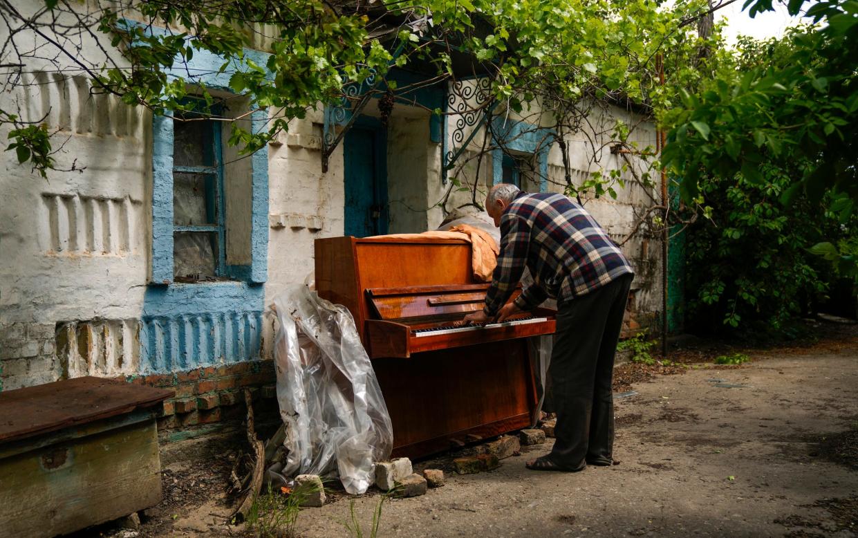 Local man Anatolii Virko plays a piano outside a house damaged after a Russian bombing in Velyka Kostromka village in Ukraine - AP Photo/Francisco Seco