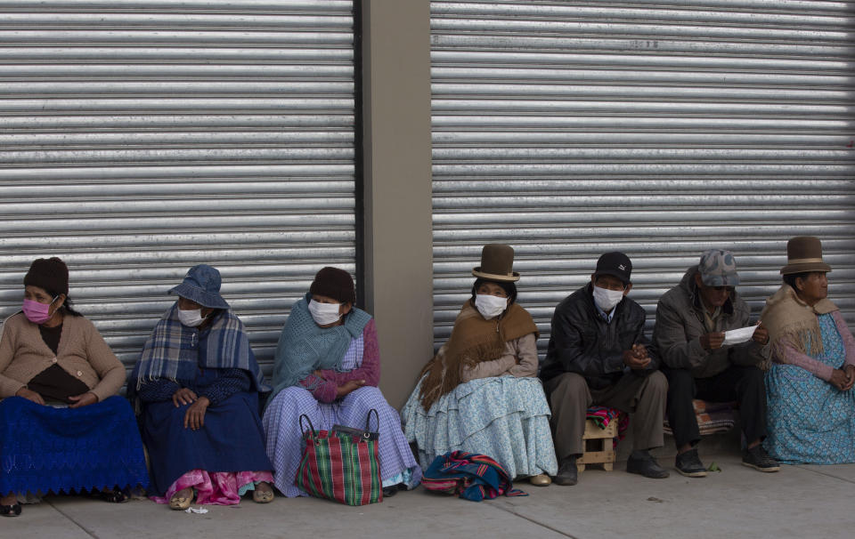 Senior citizens, most wearing protective face masks, wait in a line to receive their monthly pension in La Paz, Bolivia, Thursday, April 9, 2020, where the government has restricted residents to essential shopping in the mornings in an attempt to contain the spread of the new coronavirus. (AP Photo/Juan Karita)