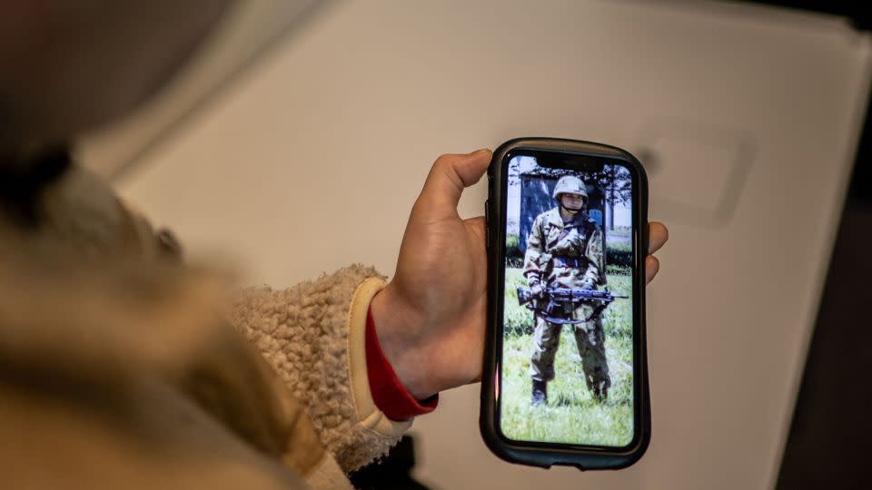 Rina Gonoi, a former member of Japan's Ground Self-Defense Force, checks old photos on her phone. - Philip Fong/AFP/Getty Images