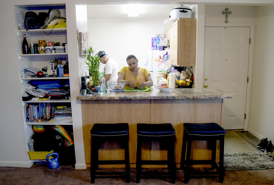 CORRECTS YEAR AND UPDATES RENT AMOUNT - Susana Rivera prepares food in her apartment, Wednesday, Aug. 3, 2022, in Steamboat Springs, Colo. Rivera tried living in the nearby town of Craig as a cheaper alternative. Every morning, she would drop her youngest child off at a friend’s house before driving 45 minutes to her supermarket job in Steamboat Springs. In 2014, she left the grueling routine behind after getting off the waitlist for an $800-a-month, two-bedroom apartment in a government-run affordable housing development. (AP Photo/Thomas Peipert)