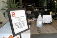 A sign is displayed near the entrance to the R. House food hall, Wednesday, July 15, 2020, in Baltimore. The hall, which houses a variety of restaurants, has modified its seating areas as well as implementing an order and pay by phone system to ensure contactless transactions between restaurant operators and customers. (AP Photo/Julio Cortez)