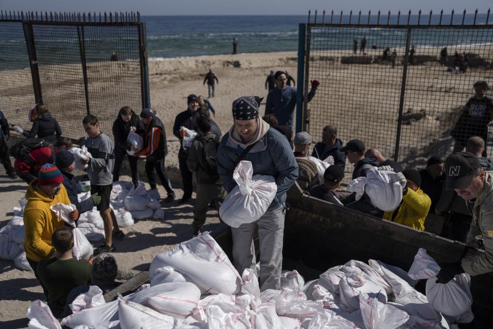 FILE - Volunteers load a vehicle with sandbags to defend the city, in Odesa, southern Ukraine, on March 23, 2022. The Black Sea port is mining its beaches and rushing to defend itself from a Mariupol-style fate. (AP Photo/Petros Giannakouris, File)